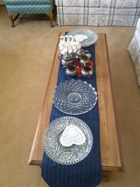 Serving glass trays, older silver-plated items, geese planter on coffee table.