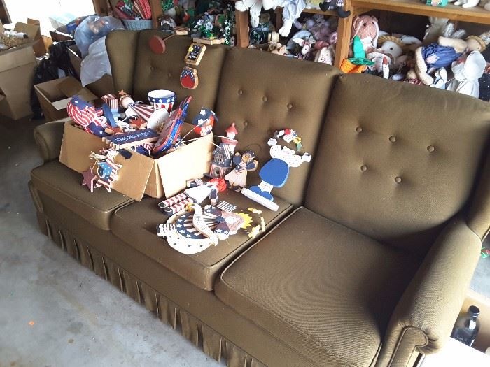 Olive Green Couch, 3 Seater, Sturdy Couch. In the garage easy to transport out. Collection of 4th of July Decorations displayed.