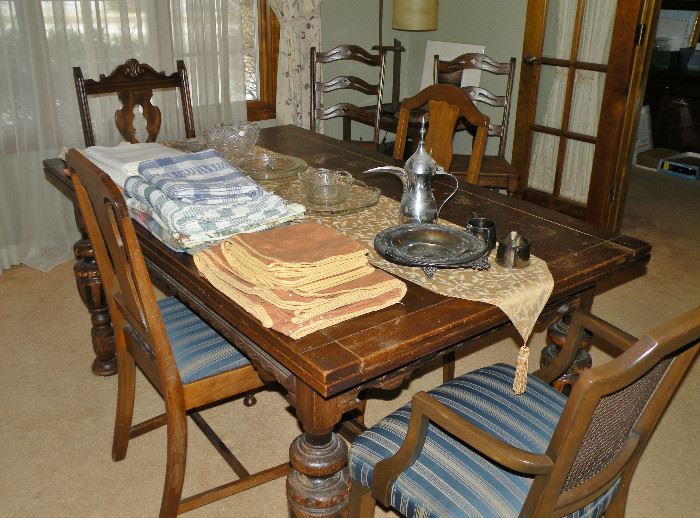 This expandable dining room table is rough. There are 5 mismatched chairs that are upholstered in this blue striped fabric. 