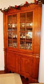 Lot 102: "Southern walnut one piece corner cupboard, having 16 panes with fluted corners, raised doors below yellow pine back boards, unusual arched sinuous carving on cornice and repeated on 3 shelves,
large bracket base with drop carved skirt, probably coastal NC in origin, ca. 1800, 7'5"" H, 56""W
possibly Tyrell County, NC.  Oral family history states cupboard came from Prospect Hill Farm, NC.  Cupboard has been reduced in height and restored to fit into today homes.  Restoration extremely well done, cupboard reduced at top section, feet appear to be original in height. (6)
"
