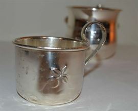 Lot 113: 2 Sterling silver baby cups, 1 monogrammed "Anne Josephine Littlepage July 27-1917, Wiley Earl Mitchelle Jr, May 22-1941", other smaller baby cup contains engraved cherry.  Dented, 3.28 total weight toz. (13)
