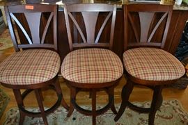 Lot 304: Set of three wood swivel bar stools with cushion seats; 45"h, mahogany finish
