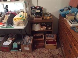 vintage beauty cases, box of various calculators, embroidery hoops, small bookshelf, crochet placemat sets & casserole carrier made by owner