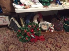 close up of wreaths - to the left on floor is baby food christmas tree that lights up (green) have another one in blue. box full of tinsel in white & silver,tree skirt