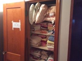 Large storage closet in hallway filled with pillows, bath towels, hand towels, and washcloths