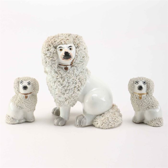Staffordshire Dog Figurines: A collection of Staffordshire dog figurines. This collection of Staffordshire dog figurines features an off-white glaze, with textural fur patterning and black and gold details. The two small dog figurines are marked to the verso.