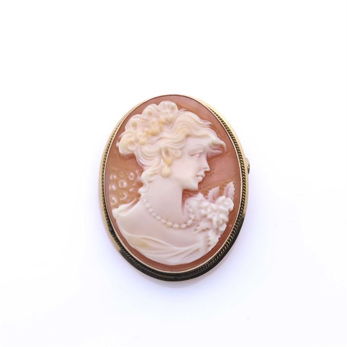 18K Yellow Gold Shell Cameo Pendant Brooch: An 18K yellow gold shell cameo pendant brooch. This piece features a high polish yellow gold bezel housing a carved helmet shell cameo. The cameo depicts a woman in profile who is wearing a strand of beads. It has a c-clasp for use as a brooch, and a hinged hidden bail for double use as a pendant.