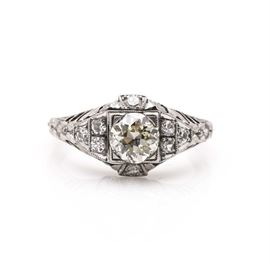 Platinum and Diamond Ring: A platinum and diamond ring. This ring features a decorative textured shank leading to ornate open work shoulders on either side of the diamond-encrusted center housing a diamond center stone with eight diamond side stones; the total approximate item weight is 2.90 dwt.