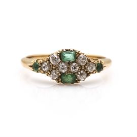 Vintage 18K Yellow Gold Diamond and Emerald Ring: A vintage 18K yellow gold diamond and emerald ring. This ring features an oval-shaped arrangement of clustered diamonds and emeralds in a high polish slightly tapered shank.
