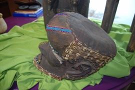 An example of one of the three accepted Kuba "royal" masks, known as M'boom or Bwoom mask. This mask has a bulbous forehead and an underslung jaw with a decorated beard.  Copper alloy ornaments the forehead, nose, and the mouth. The helmet mask  is nicely embroidered with cowrie shells and beads. This mask is well carved and beautifully decorated. It  has a lot of presence and its overall condition is very good.
In fact, without the bulging forehead which identifies "M'boom" or "Bwoom," the mask would have been difficult to categorize. This is probably due to the diverse stylistic elements found throughout Kuba territory, as the mask has features more commonly found among the Kuba sub-groups. "Bwoom" represents the evil brother in ceremonial reenactments of Kuba mythology, as well as the inevitable struggle for power among individuals. In these dances, Bwoom seeks both the mythical throne of his brother, "Mwaash A Mboy," as well as the king's wife, "Ngaady A Mwaash." Bwoom, a pygmy, s