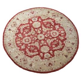 Pakistani Ziegler Handknotted Round Area Rug: A Pakistani Ziegler area rug. This 8-foot, round rug features a brick red field with a cream foliate and palmette pattern, and a cream border with a floral vine and palmette motif.