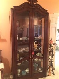 Tall display cabinet with glass front and sides and filled with "pretties"