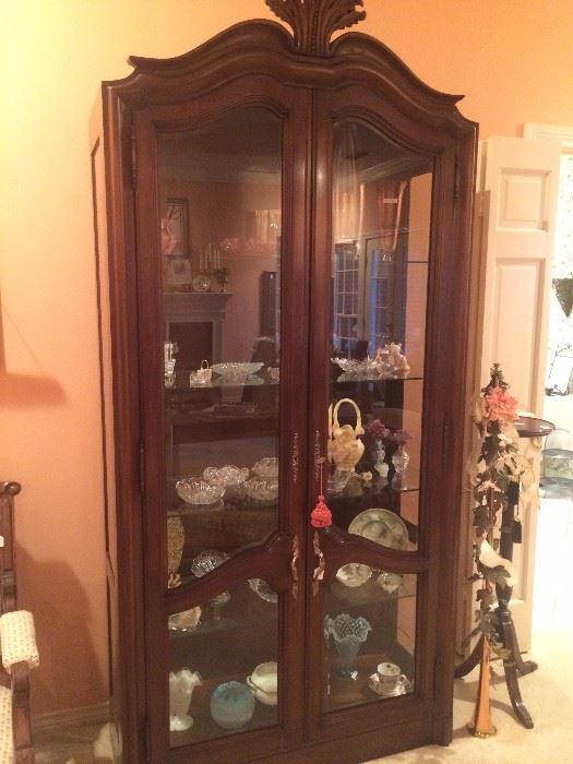 Tall display cabinet with glass front and sides and filled with "pretties"