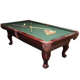 Pool Table: A pool table. This piece features a green felted surface with mahogany finished wood body. It rests on four claw and ball feet. Table has six leather pockets and includes a protective cover. Also included are two sets of pool balls and an assortment of pool cues. Please bring necessary tools to disassemble.