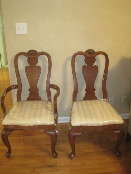 One of two Broyhill host chairs and one of 6 side chairs ( all have fitted plastic covers on seats) for dining table