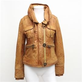 K. Maya Japanese Brown Leather Jacket: A tan leather jacket by K. Maya. This soft leather jacket, made in Japan, has two zippered hand pockets and two flap style chest pockets. It has a tall collar with a zipper that houses a cotton fold away hood. The sleeves are finished with a similar cotton material at the cuffs. There is a ribbon and metal detail running the length of the front on one side of the hidden zipper closure. It is lined in a black material and is a size L.