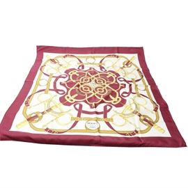 Hermès "Eperon d'Or" Silk Scarf: A silk scarf by Hermès in the Eperon d’Or pattern designed by Henri d’Origny. This square scarf has a printed design consisting of red and tan colored belts with gold colored buckles and ovation curved bits. These are rendered on a white background. The scarf has a wide red border. The edges are rolled and hand-stitched.