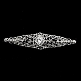 Pierced 14K White Gold Filigree and Diamond Brooch: A 14K white gold vintage brooch with a center diamond. This circa 1930s brooch features an elongated diamond shape of pierced white gold filigree. Set in the center is a single old European cut diamond.