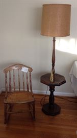 Beautiful antique rocking chair, hand craved back and rattan seat. Family left note card on chair stating description and original owner. Tall one piece lamp and side table combine to make this piece a part of history but dates back to the 50's.