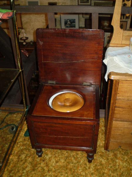 Open commode with wooden lid on porcelain pot