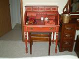 Writing desk with roll top. On the right is a part of the dresser that matches the chest of drawers and bed.