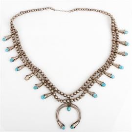Navajo Sterling Silver and Turquoise Squash Blossom Necklace: A Navajo sterling silver and turquoise squash blossom necklace It features a classic squash blossom design, featuring a Naja center pendant along two strands of round beads accented by turquoise nuggets mounted in tulip bezel settings with saw-tooth edges.