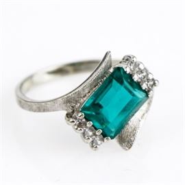 10K White Gold, Green Glass, and Cubic Zirconia Bypass Ring: A 10K white gold ring featuring a center emerald step cut green glass stone flanked by cubic zirconia on a textured bypass style shank.