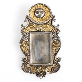 Sergio Bustamante Signed Sterling Silver Brooch: A signed sterling silver convertible picture brooch and pendant by Sergio Bustamante. The design features a carved sun atop carved scrollwork with two birds at the base and a rectangular mounting in the middle for placing a photograph. The verso features a straight pin and safety clasp along with an integrated loop. It is signed Sergio Bustamante and marked “Mex. 925, GA39” with a total approximate weight of 1.19 ozt.