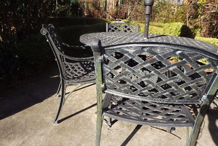 Detail of wrought iron table with 4-chairs, umbrella and base