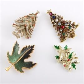 Christmas Themed Brooches: A group of four Christmas-themed brooches. This includes a gold toned Christmas tree with multicolored rhinestones marked “Holly Craft”, a Christmas tree with small rhinestones marked “Art”, a bell and holly one marked “Gerry’s”, and a green and gold toned leaf brooch.