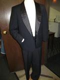 A hand tailored vintage tuxedo labeled "Luxury Lined Palm Beach woven by Goodall-Sanford". This tux is great. It is lightweight wool with black satin trim. The jacket is 30" long, and the pants have a 29-30" waist and a 30" inseam. It is in marvelous ready to wear condition. Come and try one on at the preview!