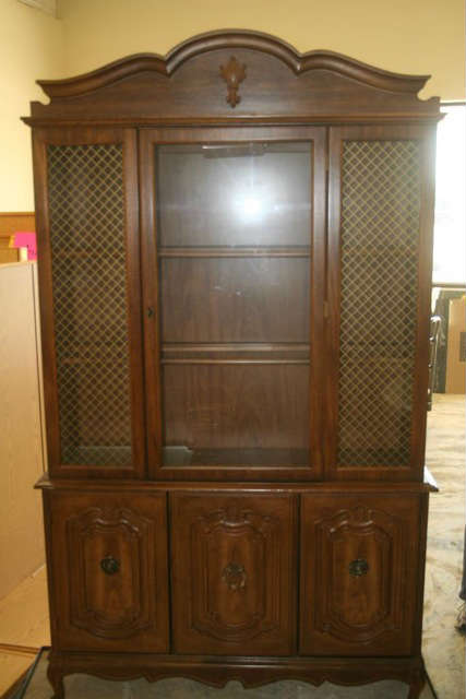 A China Cabinet in excellent condition, with a lighted top section, where two shelves are behind the glass. The bottom section has three doors with one shelf behind the door.  This measures 48"w X 78 1/2" l X 14" d. The label on the back says constructed of selected matched veneers of exceptional quality.