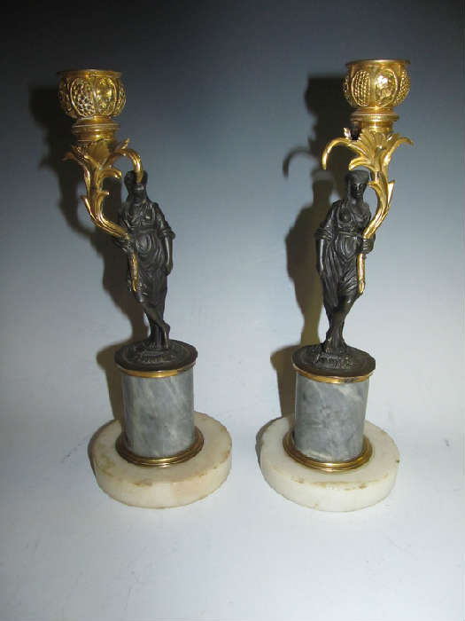A fabulous pair of French bronze dore or ormolu candelabra. One is slightly taller than the other (9.75" and 9.5"). Each features a lovely cast bronze draped lady holding a gilded bronze candleholder that is exquisitely cast in a floral pattern. And each sits upon a gray marble plinth with a white marble base. This pair is circa mid to late 1800's.
Condition: except for age expected issues (small marble flakes and stains, and one of the candleholders is a bit loose), the pair is on good condition.