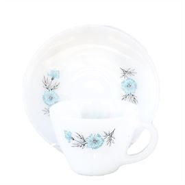 A Twenty-Five Piece Collection of White Fire King Cups and Saucers with Blue Flowers: A twenty-five piece collection of White Fire King cups and saucers with Blue Flowers. The white dishes feature blue flowers on both sides of the plate and on the front of the cups. Each dish is marked “Fire King Ovenware”.