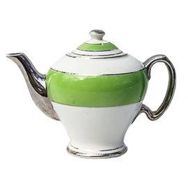 McCormick & Co Banquet Teas Teapot: A McCormick & Co Banquet Teas teapot. This teapot is white and green in color with a silver tone handle and spout. The silver tone detailing is also seen throughout the lid and along the body of the teapot. The marking on the bottom reads “McCormick & Co Banquet Teas Balto.”