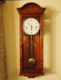 Lot 27: A contemporary English walnut "The Essex" wall clock by Comitti. Eight-day, quarter-hour strike, Westminster chime movement. Arched pediment above a single glass door opening to an enamel dial with black Roman numerals, marked "Comitti, London, 1850". With key. Model number C3260CH. Good condition. Running when catalogued. 9 3/4 x 26" high. ESTIMATE $400-600