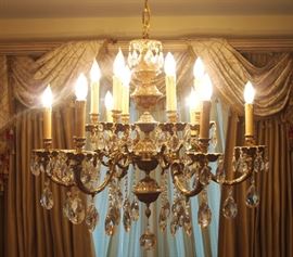 Lot 9: A European patinated metal twelve-light chandelier. Scroll arms with lights arranged in two tiers, having a gilt patina, hung with crystal prisms. Good condition. 30" diameter, 29" high. ESTIMATE $800-1,200