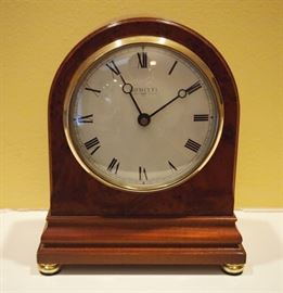 Lot 60: A contemporary English yew "The Regency" mantel clock by Comitti. Regency style, yew case with burr veneer, white enamel dial with black Roman numerals, raised on four brass feet. Battery operated. Model number C4402RC. The case is in good condition. 6 x 7 1/2" high. ESTIMATE $100-200