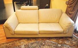 Lot 2: A Roche Bobois leather sofa. Upholstered in chamois leather, with headrest, the frame trimmed in mahogany. Labeled: Roche Bobois, Made in Italy. 85" long. Very few minor creases to the leather and scratches to the supports; overall, good condition. ESTIMATE $ 2,000-3000