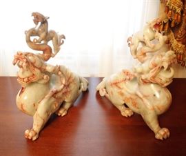 Lot 50: A pair of Indonesian hardstone guardian lion sentinel figures. Light green with red veins, each carved baring teeth, surmounted by a smaller lion. One small lion with chipped front paw; the other large figure has a repaired leg. 12 x 11" high. ESTIMATE $200-300
