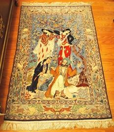 Lot 26: A 3.5 x 5.4' Indo-Persian pictorial rug. Depicting a bearded man with three female attendants beneath a flowering tree with perched birds, the border is adorned with various animals. In shades of blue, brown, red, pink and green. Light wear. ESTIMATE $600-800