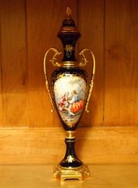 Lot 81: A French porcelain covered urn. Sevres style, hand painted at one side with an 18th century style courting scene, illegibly signed, on a cobalt blue ground with gilt accents and metal mounts. Cover is fixed. Good condition. 12 1/2" high. ESTIMATE $100-200
