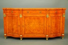 Lot 16: A contemporary Italian Neoclassical sideboard. Burl walnut with banded edges and inlaid detail with bronze, serpentine top over three conforming drawers and three lower doors, raised on brass feet. Slight wear. 72 x 19 x 36 1/2" high. ESTIMATE $1,000-1,500