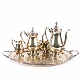 International Silver "Camille" Tea Service: An international silver Camille tea service. The service includes a tea pot, a coffee pot, a creamer, an open sugar bowl and serving tray. Each piece has a monogrammed “C” and features a floral motif around the bases and rims. The tray features a scrolled foliate design on the bellowed interior that extends out to a grooved rosette design on the edges that is accented with two scalloped handles. They are each marked “Camille, International Silver Company” with their corresponding item numbers.