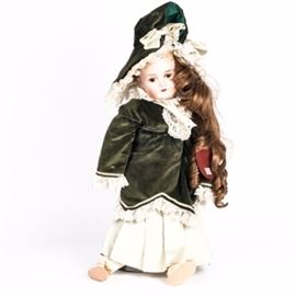 Antique Queen Louise "Jullien" Porcelain Doll: An antique Queen Louise “Jullien” porcelain doll. The doll features a porcelain head with brown hair and brown eyes. She wears a green velvet dress with matching hat that are each accented with white lace. A pair of gold tone shoes with a floral faux pearl attached complete her outfit. She has composite hands and legs and also features sleeping eyes. The back of the doll’s head has an impression that reads “Germany, Queen Louise, 9.” She also features her original Cheri’s Collection tag with her name “Jullien”.