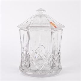 Anne Hutte Molded Crystal Biscuit Barrel: A crystal biscuit barrel made by Anna Hutte. The barrel is made of molded crystal and features a diamond pattern to the base and a lid with a curved top. The lid also features a handle to the top for easy removal. This piece is marked to the lid with a sticker reading “24% PbO, Anne Hutte.”