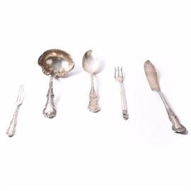 Assortment of Sterling Silver Serveware: An assortment of sterling silver serve ware. Included is a ladle marked “Sterling” and featuring a scalloped bowl with dotted floral pattern handle. A Mansfield & Baird Spoon marked “Mansfield & Baird” and “Sterling” on the transition. A Reed and Barton master butter knife marked on the transition “Sterling Pat.1899”. Also included is a Royal Danish cocktail fork marked “U.S.A” over “Royal Danish” over “international sterling”, and a sterling fork marked “Sterling, Pat. 1892”. The total combined weight is 5.26 ozt.