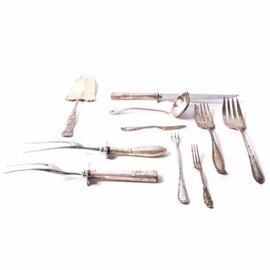 Group of Silverplate Serveware: An assortment of silverplate serveware. The set includes two seafood forks, two cocktail forks, two meat servers, a pastry knife, a ladle, a carking, and a sterling weighted knife. Brands include Holmes & Edwards, WM. Rogers & Son, among others. Designs vary from piece to piece.