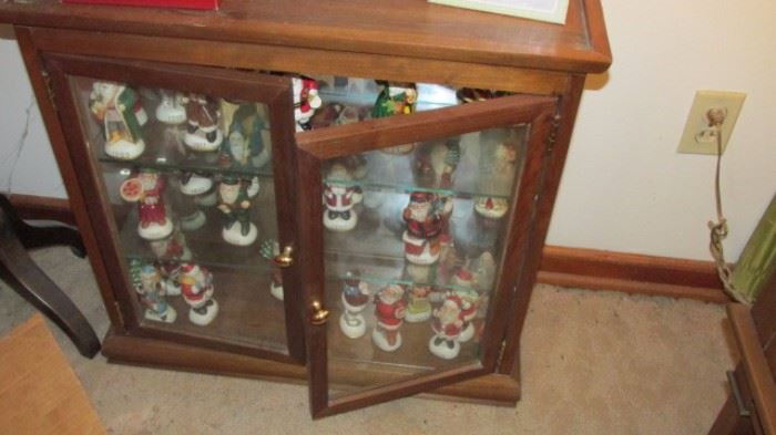 Walnut curio stand filled with Santa Figures