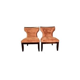 Matching Pair of Upholstered Chairs: A matching pair of upholstered chairs . The pair has two chairs with a metropolitan styling that are wood with a dark brown stain and feature a curved and tapered upholstered back ,flared seat and wood seat rails with tapered wood block legs. The upholstery is a pastel orange velvet with a tufted button back and cloth piping on the seat and back edge.